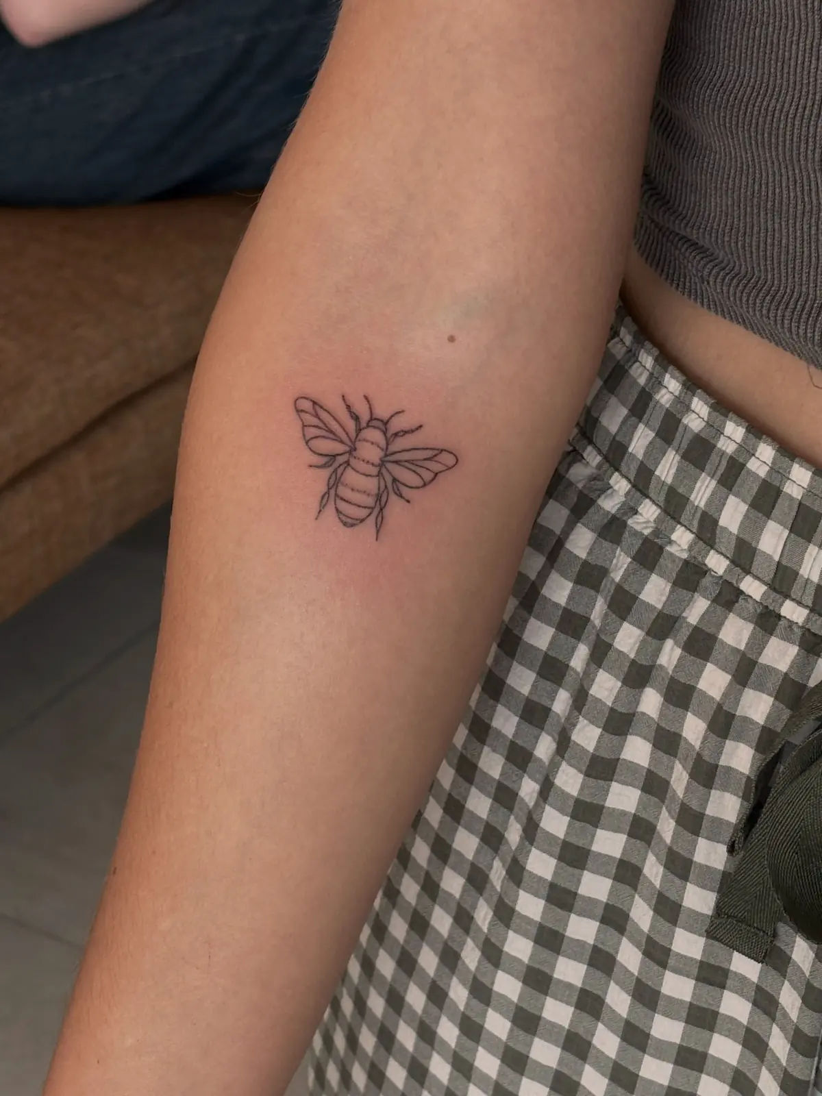 Small fine-line honeybee with lightly shaded body on a forearm.