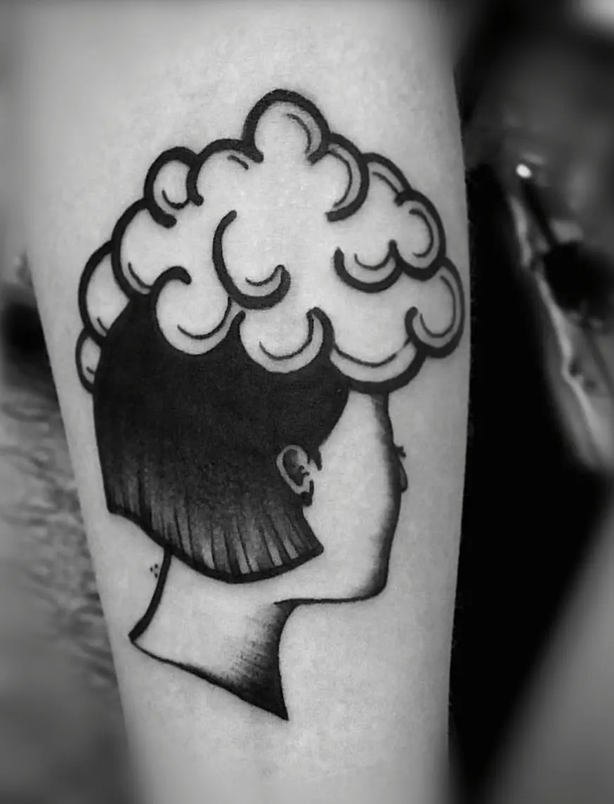 Bold black silhouette of a head in profile with outlined curly hair, on a forearm.
