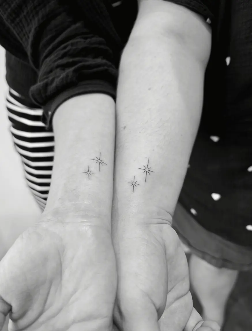 Two people holding hands, each with the same pair of tiny fine-line sparkle stars on the wrist.
