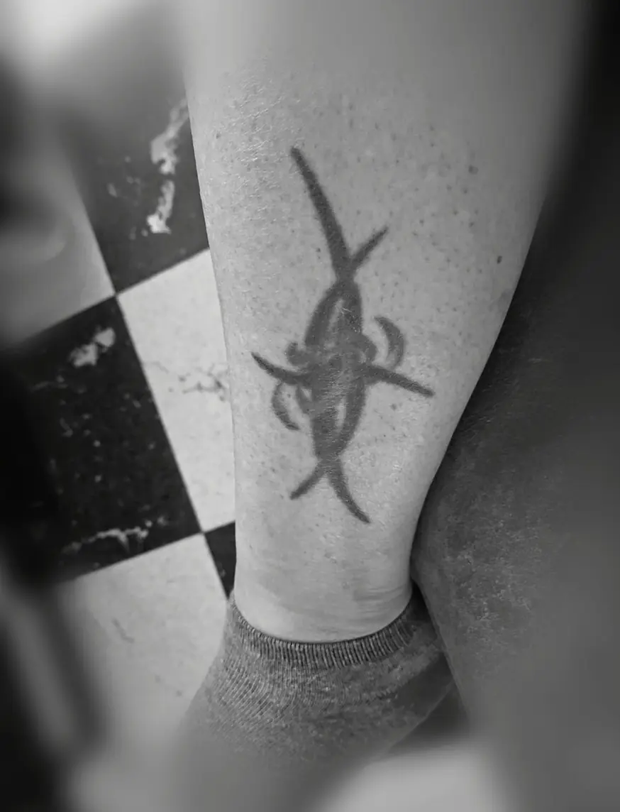 Sharp black neo-tribal shape on the back of the calf.